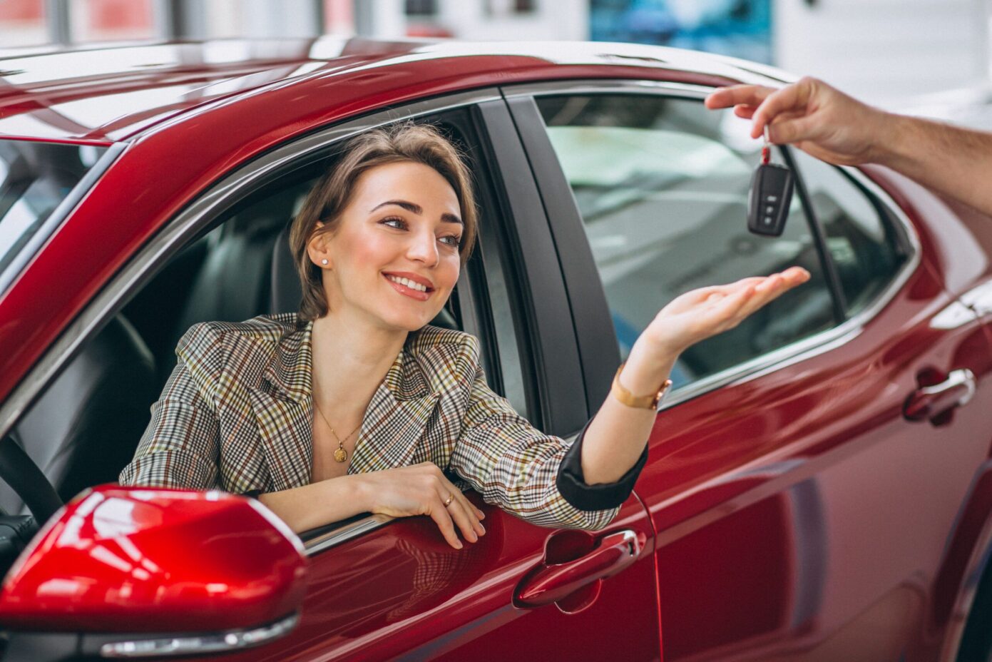 woman-sitting-red-car-receiving-keys